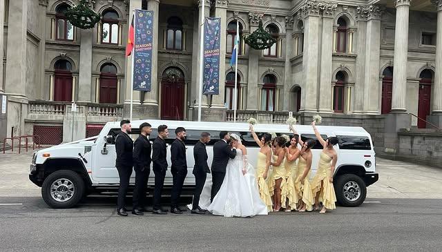 Bridal party gathered beside a Hummer limousine