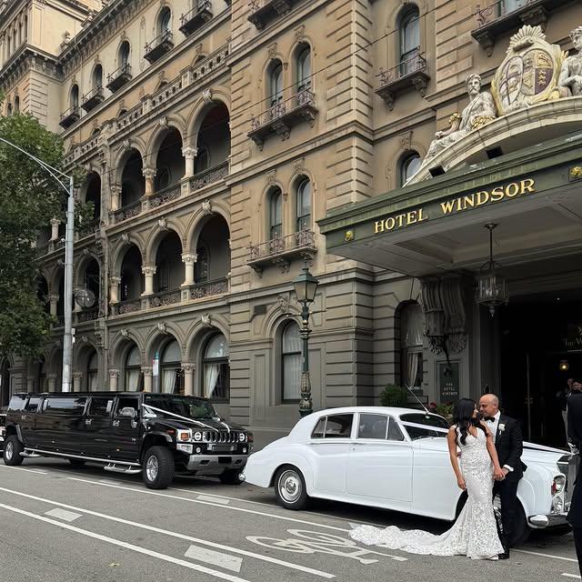 Bride and groom outside Hotel Windsor with wedding cars
