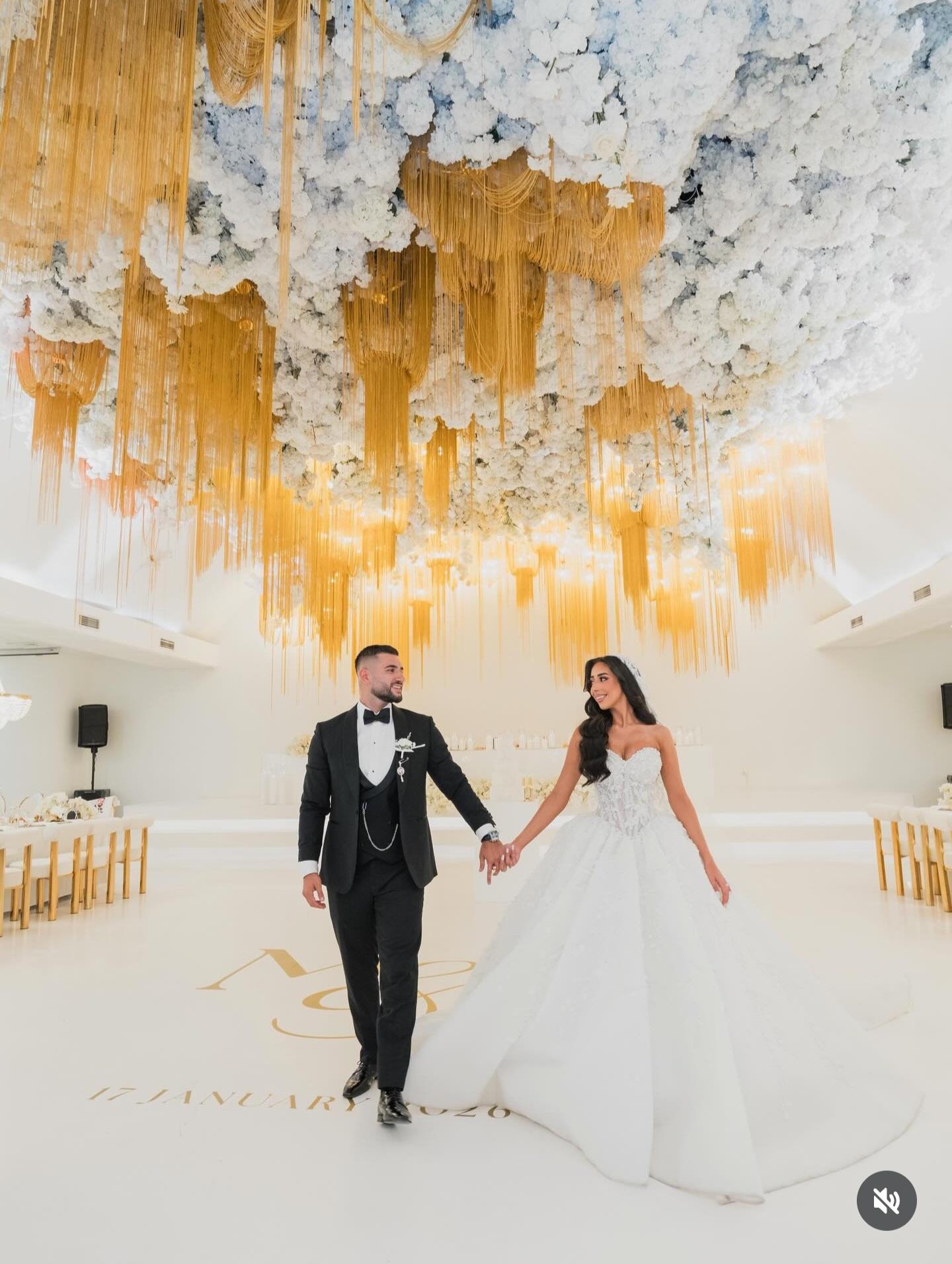 Bride and groom entering a white ballroom hand in hand