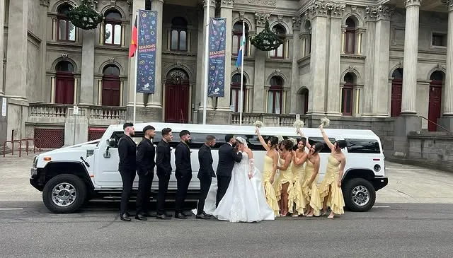 Bridal party gathered beside a Hummer limousine