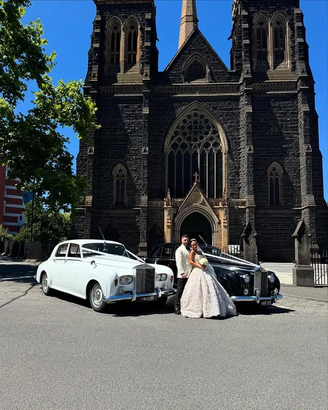 Bride and groom outside a church with wedding cars