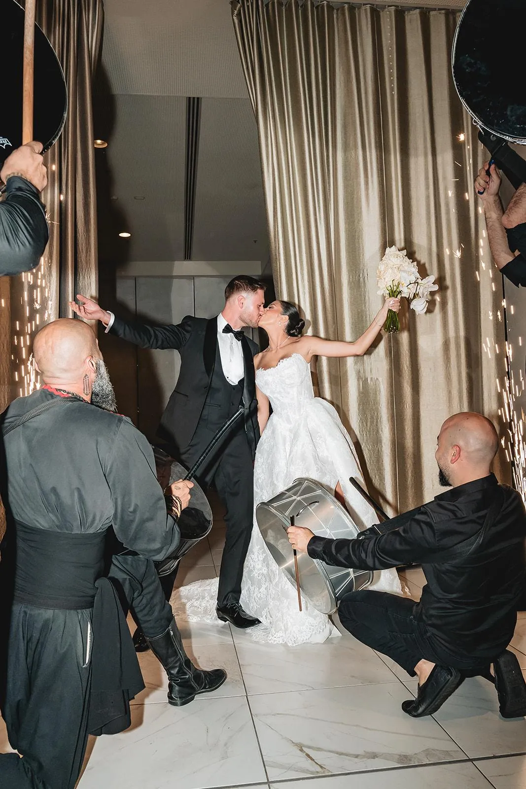 Bride and groom kissing as IAMNSA drummers perform around them
