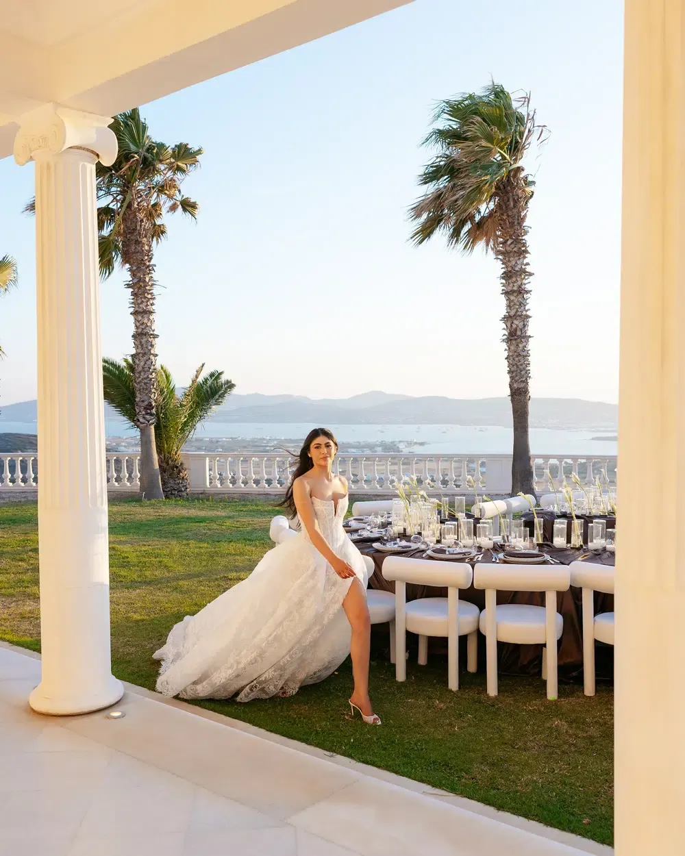 Bride walking across a lawn at an outdoor coastal reception beside a decorated dinner table