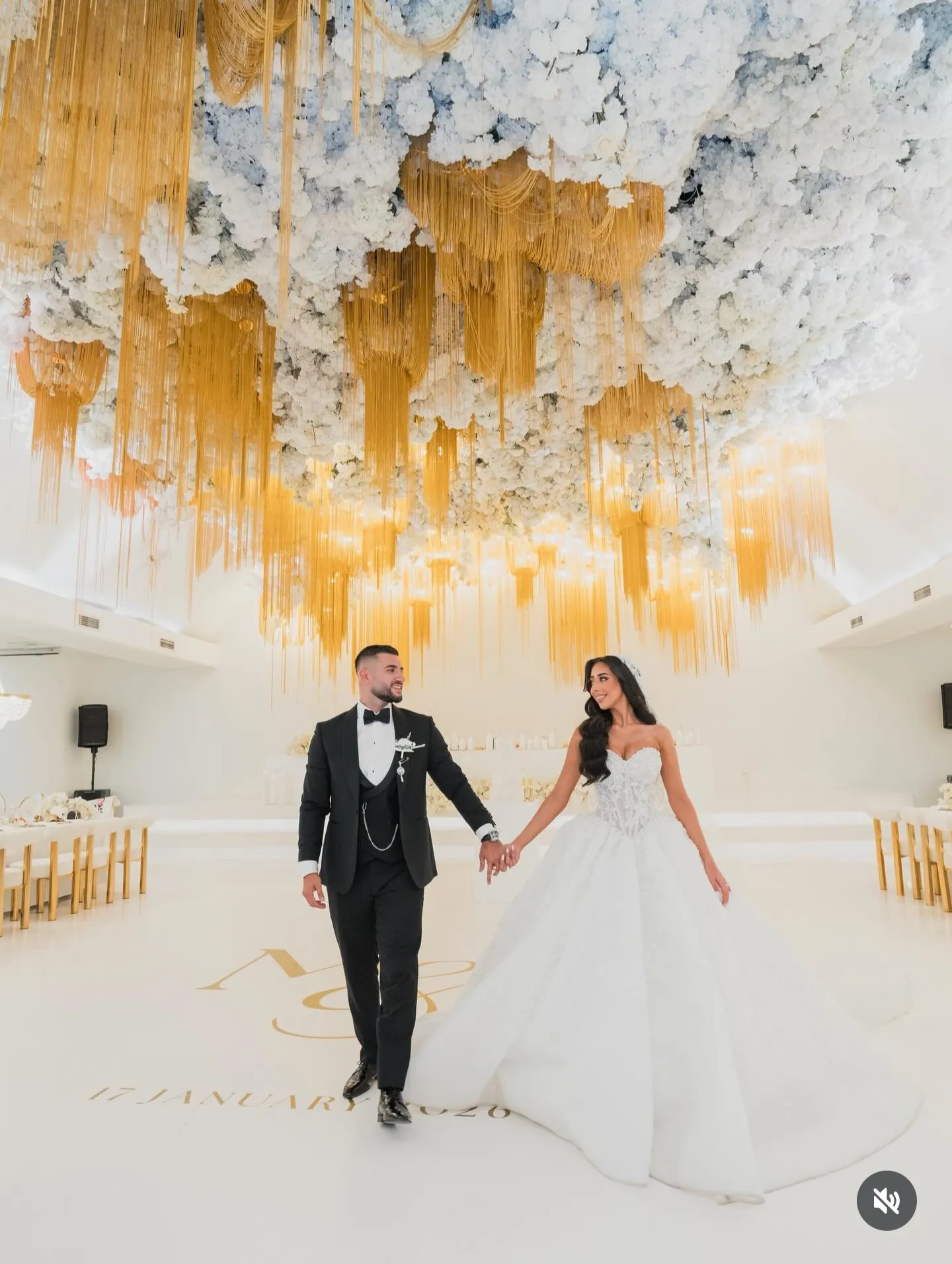 Bride and groom entering a white ballroom hand in hand