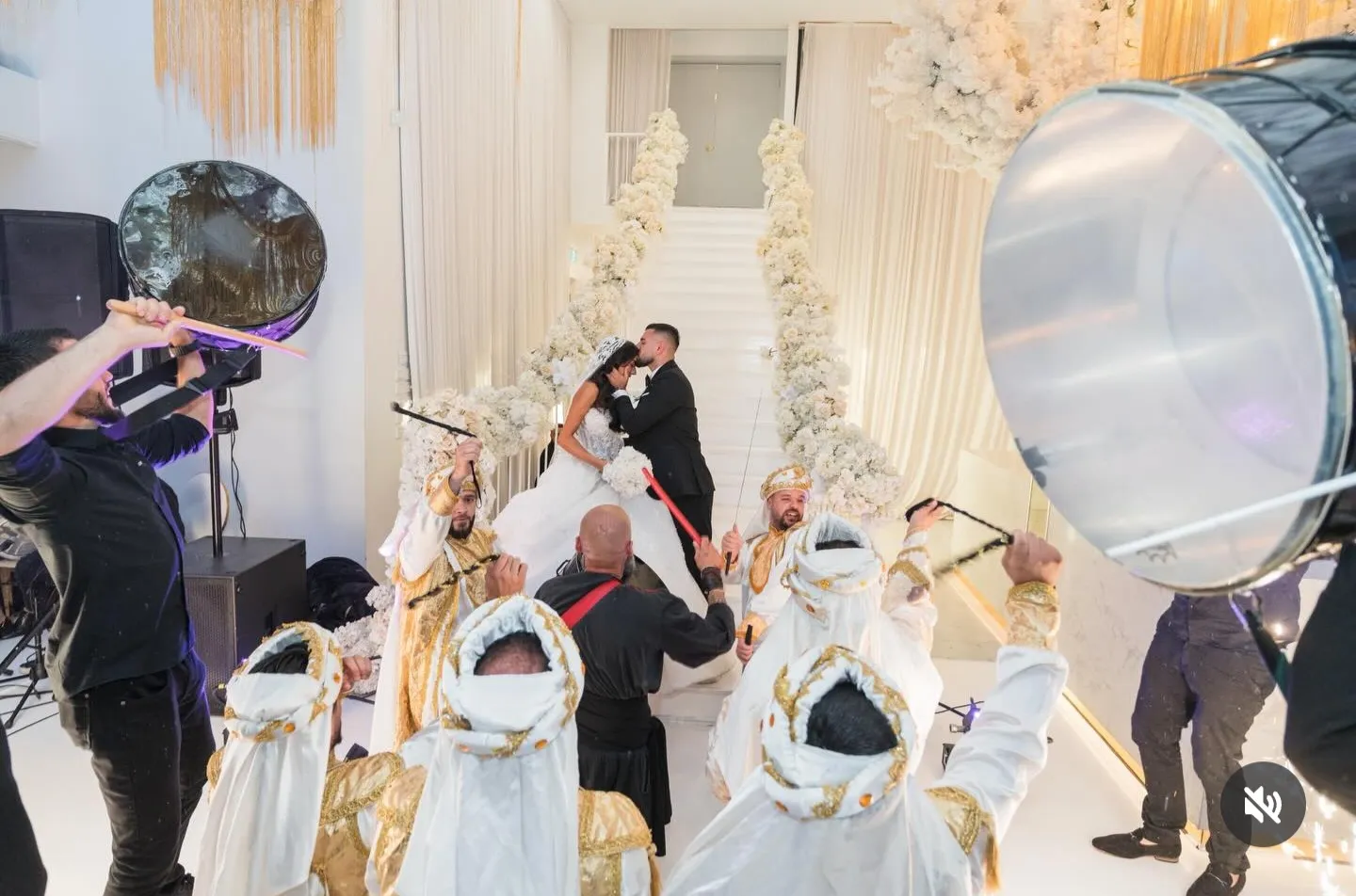 Bride and groom on a staircase with drummers and performers