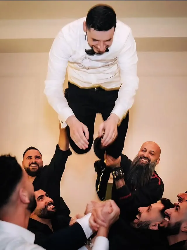 Groom lifted by groomsmen during a wedding celebration
