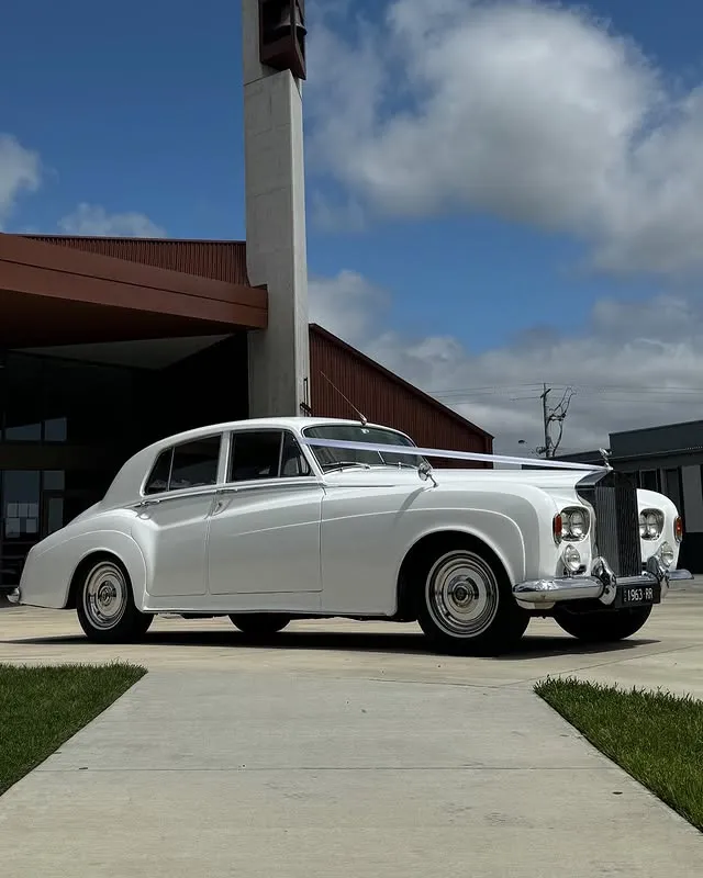 White vintage Rolls-Royce wedding car outside a venue